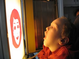 Frühförderung für Kinder mit Mehrfachbehinderung – Kind betrachtet Gesichterschema auf Lichtkasten